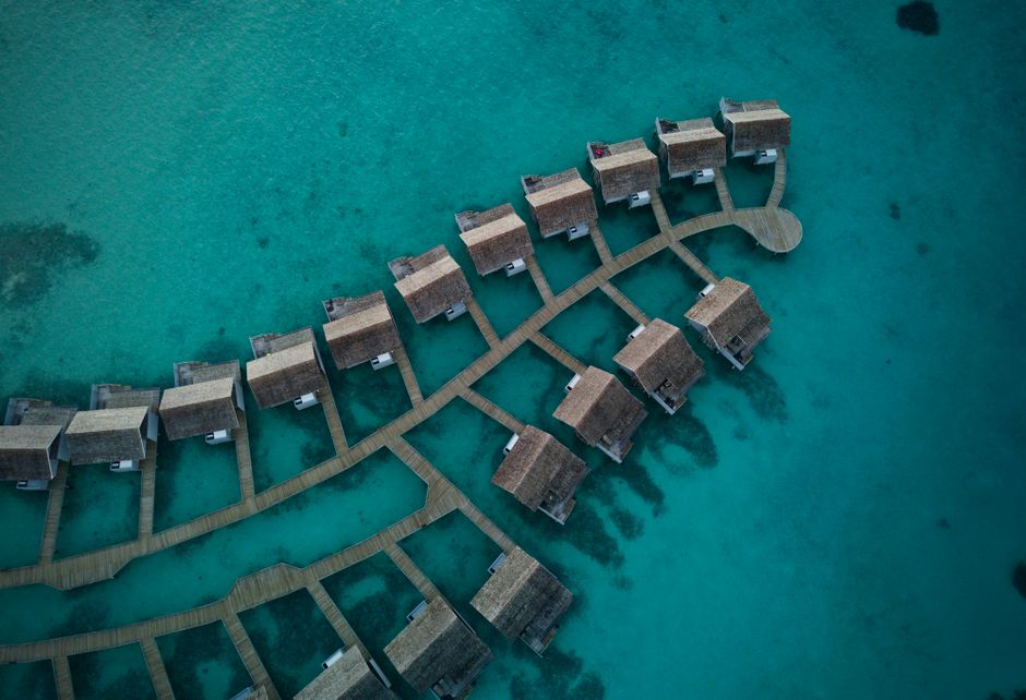 Stunning aerial shot of overwater bungalows in a tropical resort setting against turquoise sea waters.